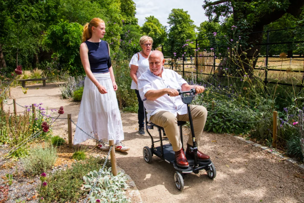 Man exploring a garden on his eFOLDi with family alongside